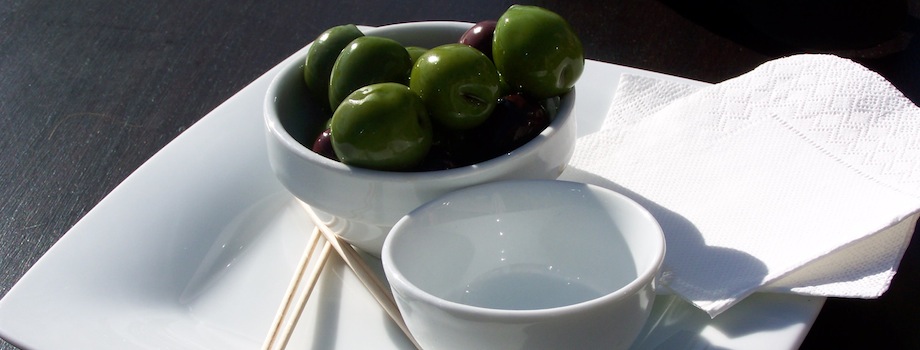 Bowl of green olives on a white plate