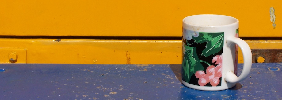 A colourful floral mug sitting alone on a blue and yellow painted surface — the Lonely Cup at Circus Raluy, Sabadell